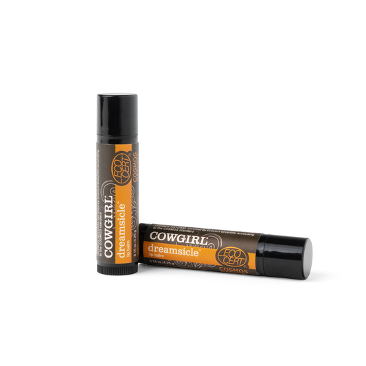 Two lip balm tubes in Cowgirl Dreamsicle, one standing upright and the other lying on its side, on a clean white background.